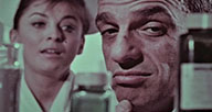 A still from a film showing a man and woman looking specualtively at medicine bottles.