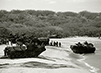 Black and white photograph of tanks and APC’s landing on beach for military exercises. 