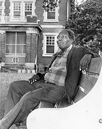An African American man sitting on a bench outside.