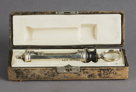 Barrel of a serum syringe in a celluloid-lined case with a hinged lid and leather covering.