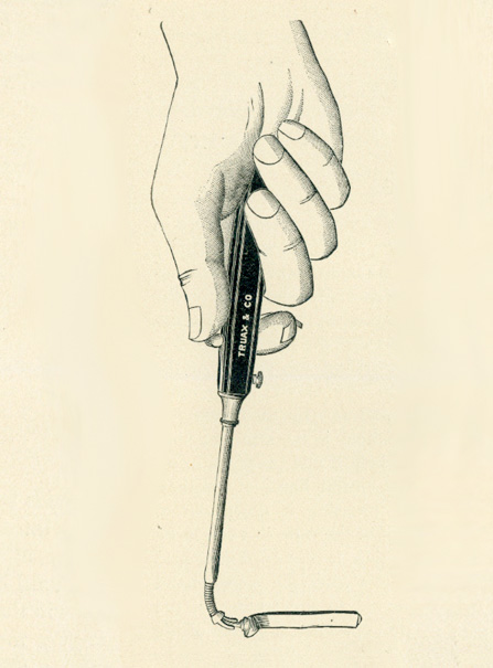 A hand holding a long tool with the thumb placed on a notch on its handle with elongated neck that curves down on its end where a tube is attached.