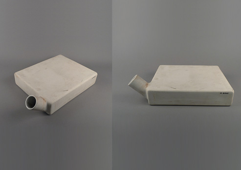 Square-sided, flat ceramic vessel with short cylindrical spout near one corner shown from the top and side.