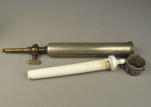 White ceramic filter tube with nipple on one end and metal pipe-like case for the ceramic filter. 