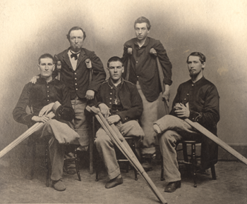 Black and white photograph of five men, each with an amputated leg, dressed in Civil War-era military uniform and holding wooden crutches.