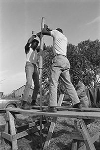 Three African American men working outside, constructing a well.