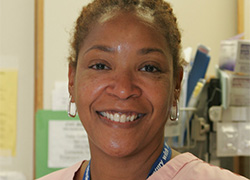 A woman smiling in pink medical scrubs.