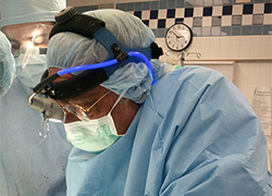 Left profile of a surgeon in scrubs preforming an operation.