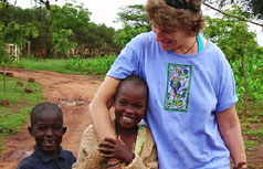 White woman walks with 2 smiling African children.