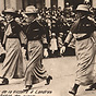Three White female nurses in military uniforms march with White boy wearing military uniform.