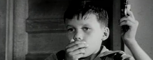 A young boy covering his mouth with his right hand.