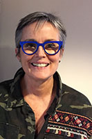 A white woman with grey hair and blue glasses.