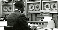 A man types in computer commands to be performed and processed by magnetic tape in the OCCS computer room.
