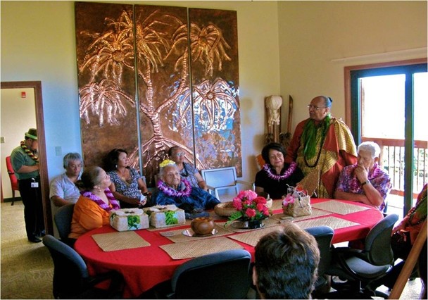 Color photograph of a group of Hawaiian elders talking while sitting around a table.
