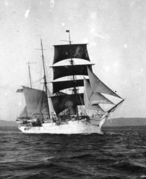 Black and white photograph of a large ship with several sails at sea.