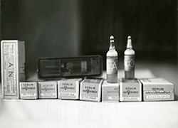 Two small vials set on two among several small boxes laying on a surface. 