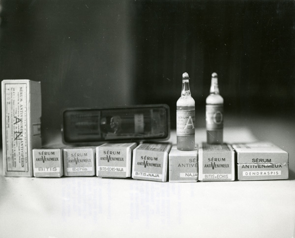 Two small vials set on two among several small boxes laying on a surface. 