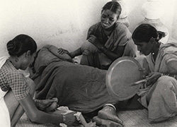 Three women seated around another laying on her side. 