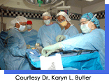 Five women in men in green surgical scrubs operating on a patient.  Courtesy Karyn L. Butler, M