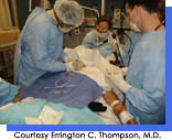 Three people dressed in blue surgical scrubs operating on a patient.  Courtesy Errington C. Thompson, M.D.