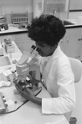 Delta Health Center staff member looks through a microscope in the laboratory