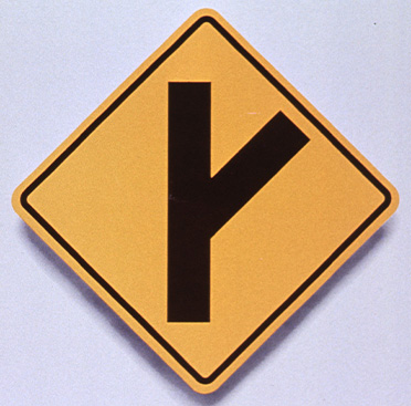 Yellow square road sign that has black line with another line branching off from it indicating branch in the roadway, above text