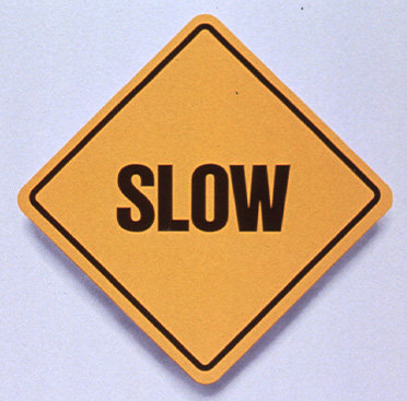 Yellow square road sign that says Slow above text