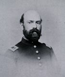 Photographic portrait, in black and white, of Charles Henry Alden, posed in three quarter view, from shoulders up, balding man with full dark beard in U.S. Army uniform.