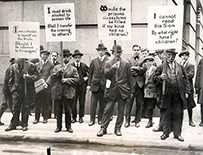 Men standing on a street holding signs.