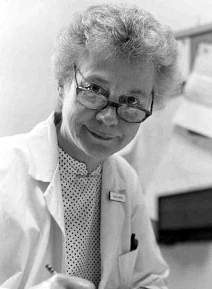 Dr. Réjane M. Harvey, a White woman with glasses in a lab coat writing in a folder.
