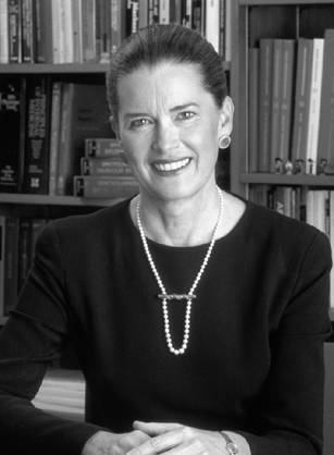 Dr. Jane Ellen Henney, a smiling White woman wearing pearls seated in front of book shelves.