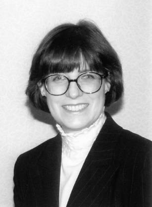 Dr. Christie Ann Huddleston, a smiling White woman with glasses in a dark jacket posing for her portrait.