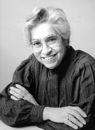 Dr. Joyce Cohen Lashof, a White woman wearing glasses and a blouse posing with her arms folded for a portrait.