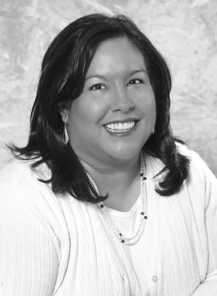 Dr. Conchita Marie Paz, a smiling Hispanic woman with dark hair and a pink sweater posing for her portrait.