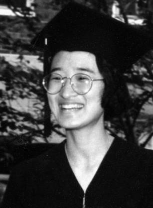 Dr. Ina Park Rhee, a smiling Asian woman wearing a cap and gown outdoors.