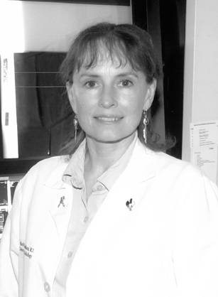Dr. Marilyn A. Roubidoux, a White woman in a lab coat posing next to a set of x-rays.