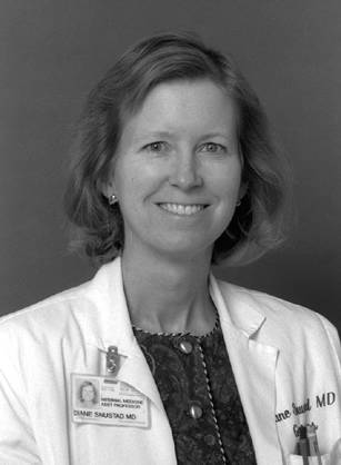 Dr. Diane Gail Snustad, a White woman in her lab coat, smiling for her portrait.