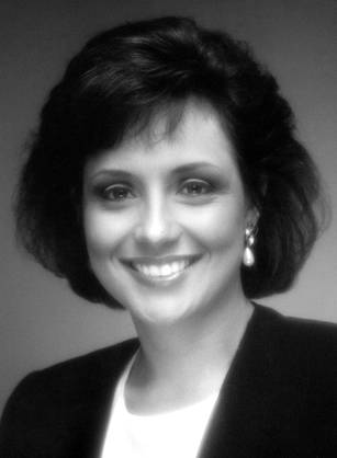 Dr. Michelle Anne Bholat, a smiling woman with dark hair in a suit and a red background.