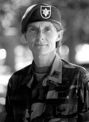 Dr. Rhonda L. Cornum, a White woman officer posing in decorated uniform in front of the American flag.