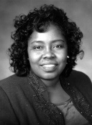 Dr. Judith Martin Cadore, an African American woman in blue formal attire posing for her portrait. Inscription: Connie's by Glenn ©.