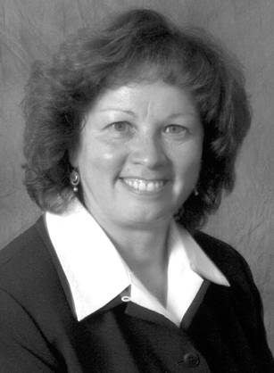 Dr. Nereida Correa, a smiling White woman in a collared shirt and sweater posing for her portrait.