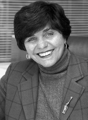 Dr. Catherine D. DeAngelis, a smiling White woman in a suit jacket seated in an office.