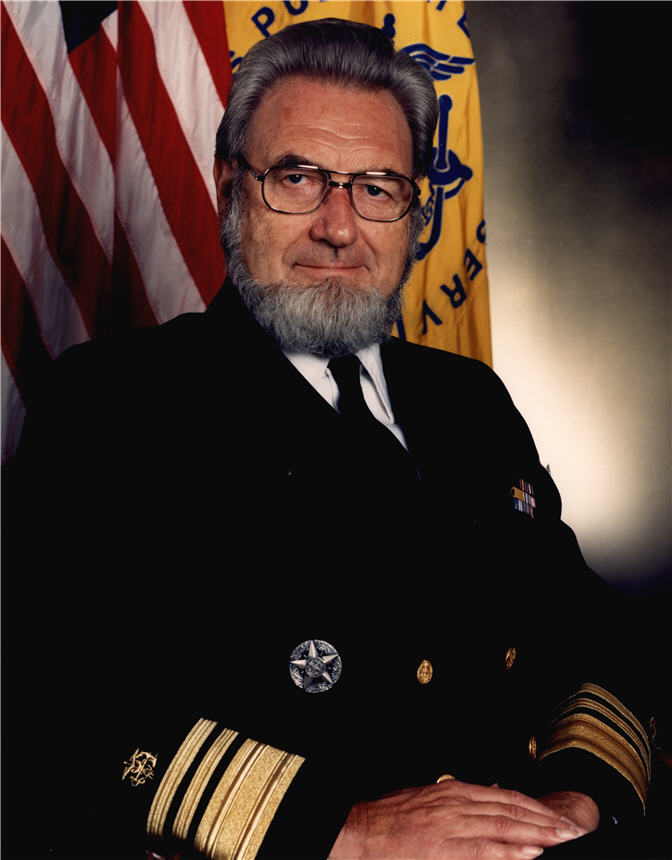 Bearded White man wearing a black military style uniform seated and looking at viewer.