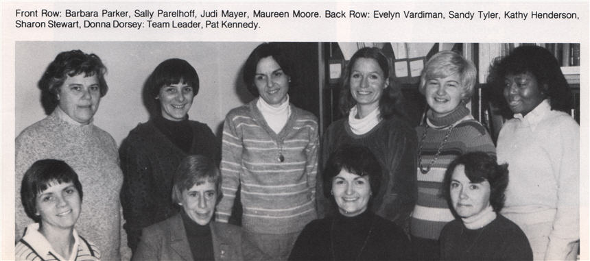 A group of 10 women face the viewer, 4 are in front sitting, and 6 stand behind.