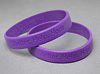 Two purple silicon wristbands, one stacked on the other.