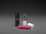 Two lipstick tubes with one opened and showing a pink rolled up paper-insert
