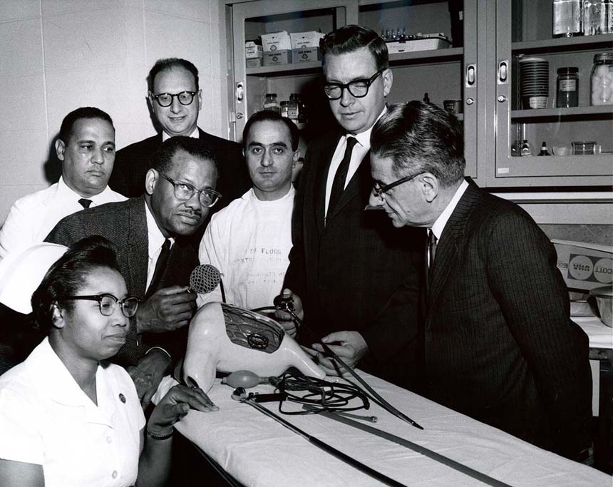 Dr. Berry posing with an international group of students
 and an assortment of medical equipment. Handwriting on back of photo.