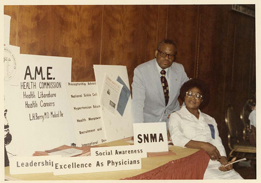 Dr. Berry standing behind a woman next to a table with AMA posters and literature.