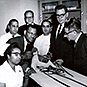 Dr. Berry posing with an international group of students
 and an assortment of medical equipment. Handwriting on back of photo.