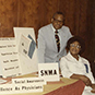 Dr. Berry standing behind a woman next to a table with AMA posters and literature.