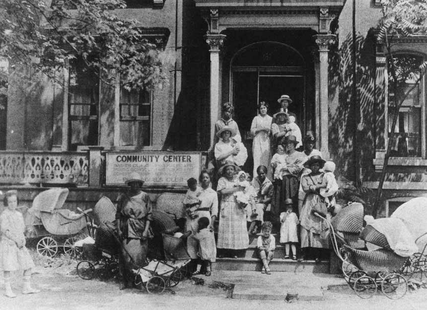 21 White and African Americans, including children, on steps of a building surrounded by strollers.